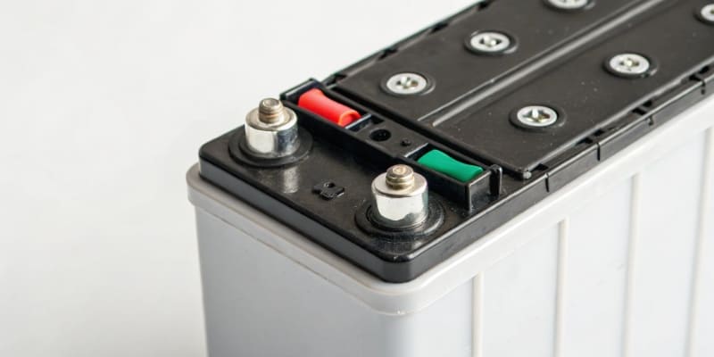 A warehouse manager checking a compliance checklist next to pallets of batteries