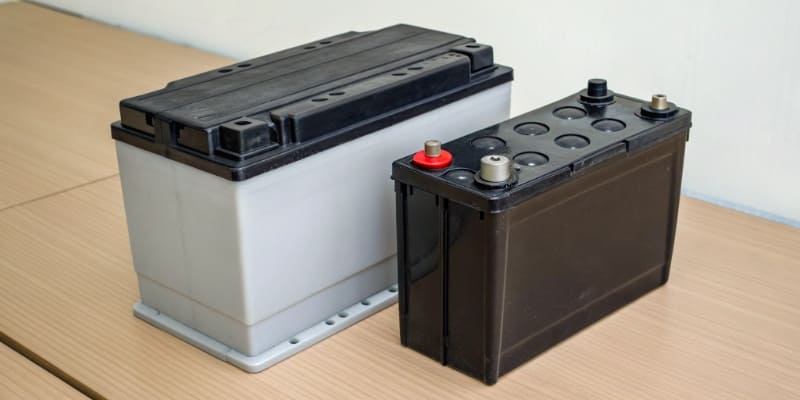 A mechanic using a digital battery tester on a car battery