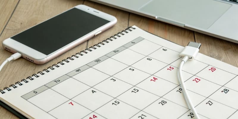 A calendar with days being crossed off next to a charging device