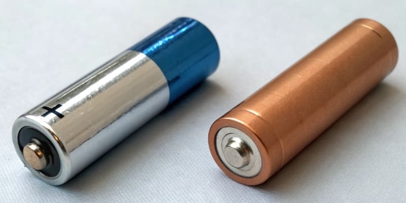 A comparison image showing an Alkaline AA battery and a Lithium AA battery side-by-side with temperature ranges