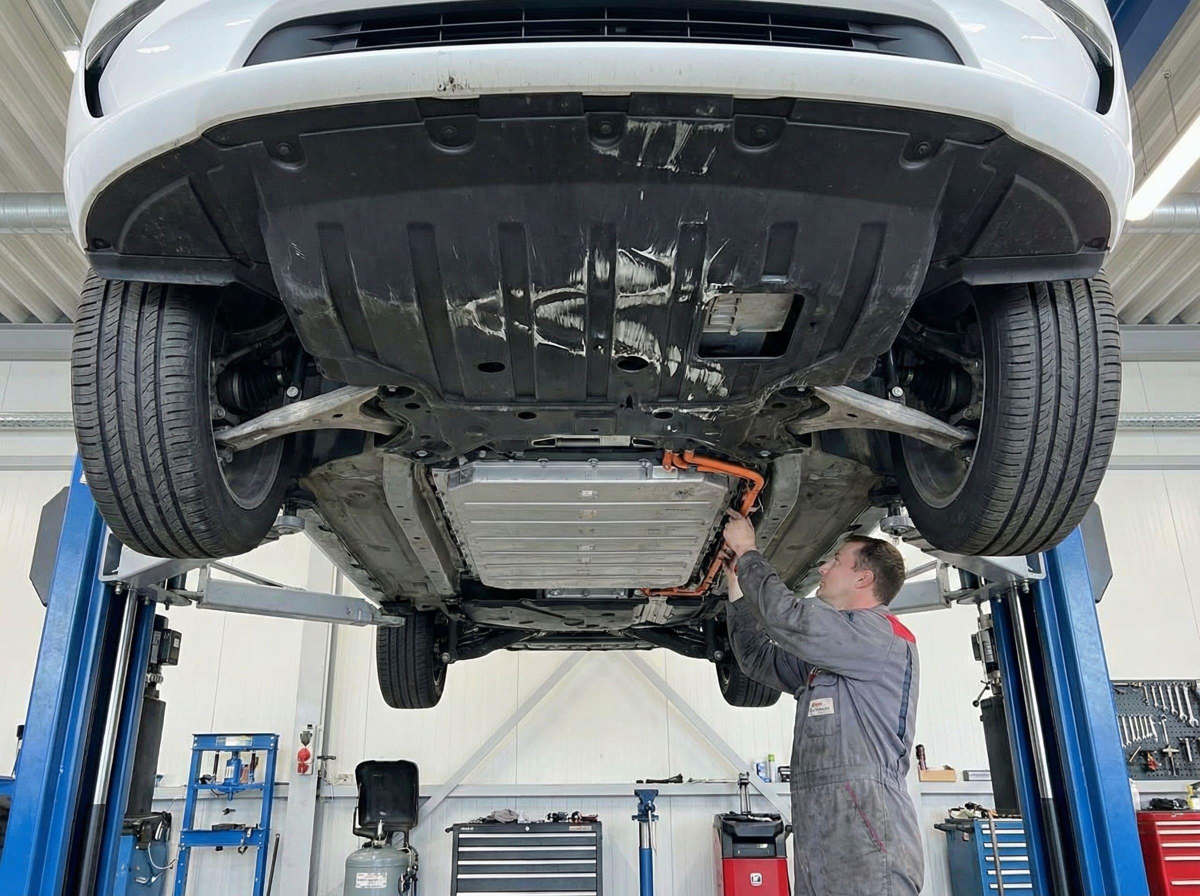 An electric vehicle on a lift showing the underbody battery pack