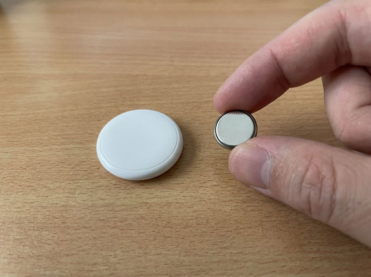 An Apple AirTag attached to a suitcase handle with a passport in the background