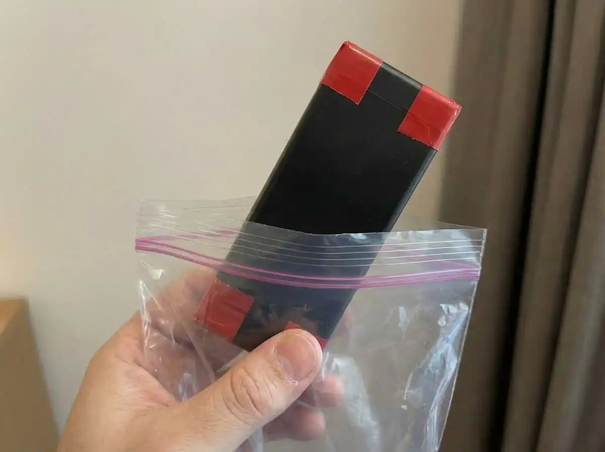 Protecting Spare Battery Terminals for Flight An image showing a battery with tape over its contacts next to loose keys and coins